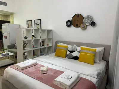 a bedroom with a bed with yellow and white pillows at Studio Apartment- Dubai Marina in Dubai