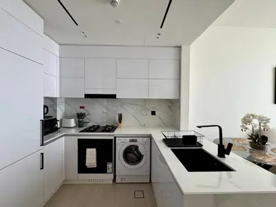 a kitchen with white cabinets and a washer and dryer at Modern & Elegant 1br Apartment In Jvc in Dubai