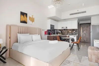 a bedroom with a large white bed and a kitchen at Lux Studio Apt near Butterfly Garden - Pool & Gym in Dubai