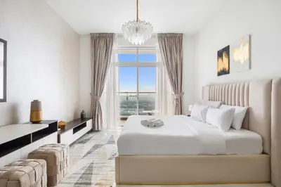 a white bedroom with a large bed and a large window at Lux Studio Apt near Butterfly Garden - Pool & Gym in Dubai