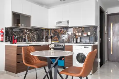 a kitchen with a table and chairs in a kitchen at Lux Studio Apt near Butterfly Garden - Pool & Gym in Dubai