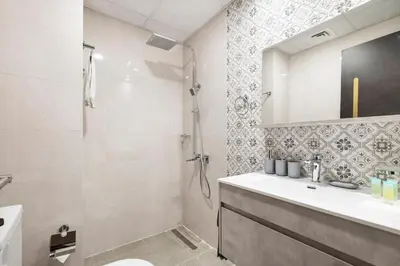 a white bathroom with a shower and a sink at Lux Studio Apt near Butterfly Garden - Pool & Gym in Dubai