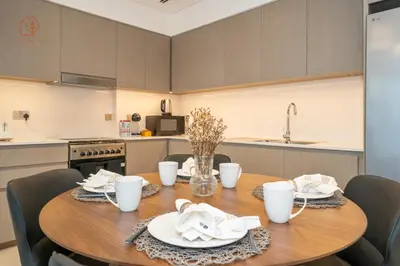 a kitchen with a wooden table with white dishes on it at Burj Khalifa Views 2-Bedroom Apartment 203GR-2 in Dubai