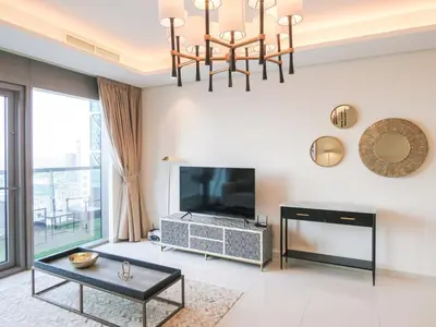 a living room with a television and a chandelier at High Floor , Premium 1 Bedroom , Stunning Views in Dubai