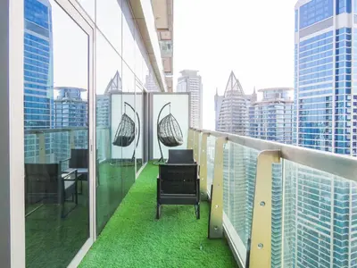 a balcony with chairs and green grass on a building at High Floor , Premium 1 Bedroom , Stunning Views in Dubai