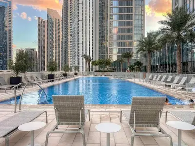 a large swimming pool with two chairs and buildings at 2BR Forte Tower 1 Downtown 3mn Burj Khalifa in Dubai