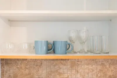 a shelf with cups and wine glasses on it at Chic Studio in Goldcrest Views, JLT in Dubai