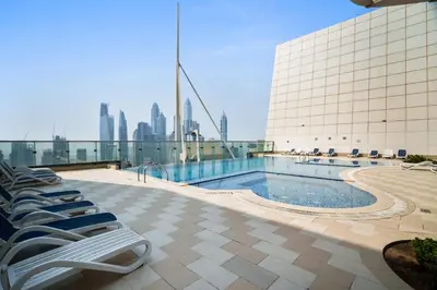 a pool on the roof of a building with chairs at Chic Studio in Goldcrest Views, JLT in Dubai