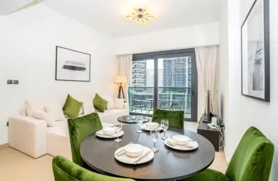 a living room with a table and green chairs at Luxury Apartment ACT One Act Two 7 Min Walk to Burj Khalifa & Dubai Mall in Dubai