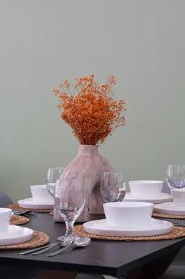 a table with plates and glasses and a vase with flowers at Downtown Skyline & Burj Khalifa Views Dubai in Dubai
