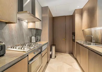 a kitchen with wooden cabinets and a stove top oven at Daniels Sea View 2BR at Five Palm Jumeirah in Dubai