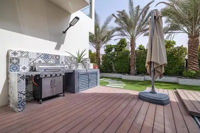 a patio with an outdoor kitchen and an umbrella at Coastal Themed 4BR Townhouse with Pool in JVC in Dubai