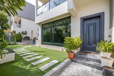 a house with a blue door and some plants at Coastal Themed 4BR Townhouse with Pool in JVC in Dubai