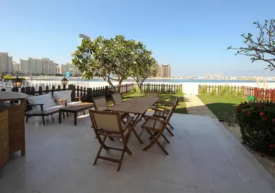 a wooden table and chairs with a view of the water at Breathtaking Villa With Roof Garden and Beach access in Dubai