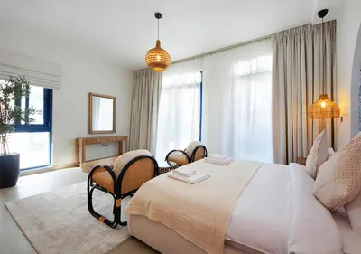 a bedroom with a large bed with chairs and windows at Breathtaking Villa With Roof Garden and Beach access in Dubai