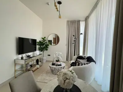 a white living room with a couch and a tv at Trendy & Elegant 1br In Jvc in Dubai