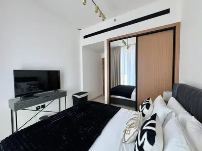 a bedroom with a large bed and a television at Trendy & Elegant 1br In Jvc in Dubai