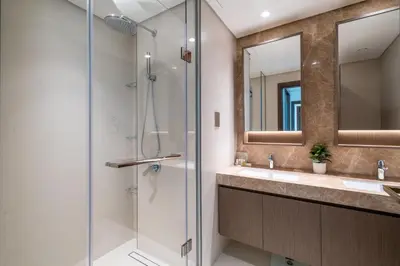 a bathroom with two sinks and a glass shower at Homes Beyond l Elegant 2BR with Wide Sea Views in Dubai