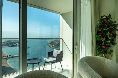 a balcony with chairs and a view of the ocean at Homes Beyond l Elegant 2BR with Wide Sea Views in Dubai