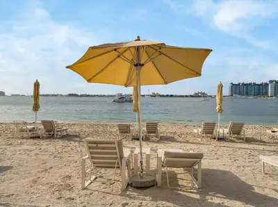 a yellow umbrella and chairs on a beach at Homes Beyond l Elegant 2BR with Wide Sea Views in Dubai