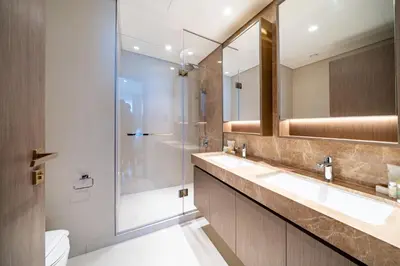a bathroom with two sinks and a glass shower at Homes Beyond l 2BR Panoramic Skyline & Sea View in Dubai