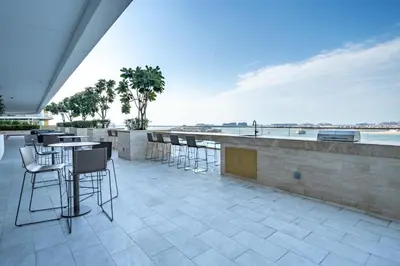 a patio with tables and chairs and a view of the water at Homes Beyond l 2BR Panoramic Skyline & Sea View in Dubai