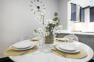 a white table with plates and glasses and a vase with flowers at Business Bay 1BR Canal Views, Pool, Gym & Near Burj Khalifa in Dubai