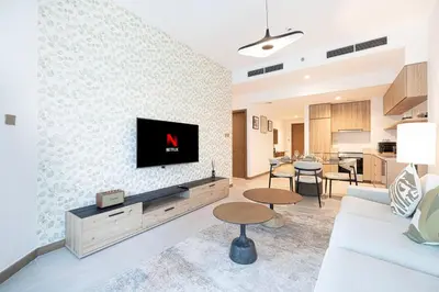 a living room with a couch and a tv on a wall at Mahogany 2 - 2BR 6PAX - Infinity Pool & Near Metro in Dubai