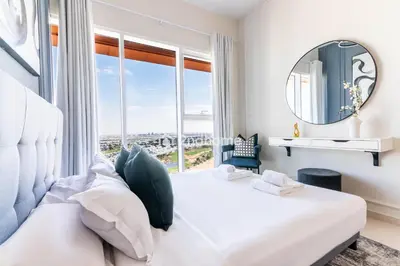 a bedroom with a large white bed with a large window at Modern 1-BR Golf Course View in Golf Vita in Dubai