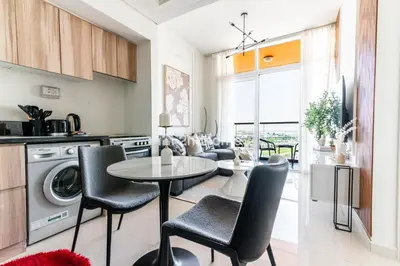 a kitchen and living room with a table and chairs at Modern 1-BR Golf Course View in Golf Vita in Dubai