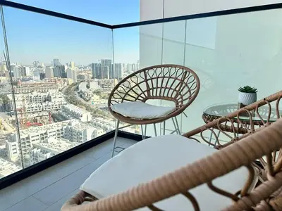 a balcony with a chair and a table and a view at Chic & Modern 1br Apt Balcony Pool Parking in Dubai
