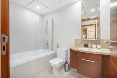 a bathroom with a toilet and a tub and a sink at Sophisticated and Elegant 2BR in Downntown Dubai in Dubai