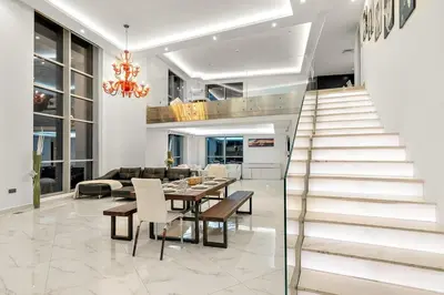 a living room with a staircase and a table and chairs at Elegant 2BR with Burj Views, Pool, Gym, and Quick Metro Access in Dubai