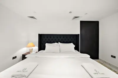 a large white bed with two white towels on it at Elegant 2BR with Burj Views, Pool, Gym, and Quick Metro Access in Dubai