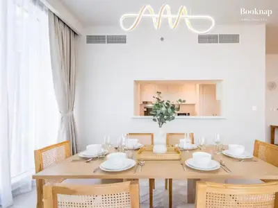a dining room with a wooden table and chairs at Lavish 3BR Apartment with Assistant Room in Habour Gate Tower in Dubai