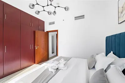 a bedroom with a bed with white sheets and a chandelier at Time Place Near Metro and Mall in Dubai