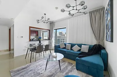 a living room with a blue couch and a table at Time Place Near Metro and Mall in Dubai