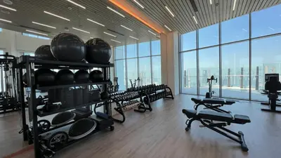 a gym with a bunch of equipment in a room with windows at Iconic 1Bedroom Duplex with Skyline Views Near Downtown Dubai & Burj Khalifa in Dubai