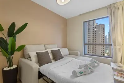 a bedroom with a white bed and a large window at Beachside Home on JBR Walk with modern interiors in Dubai