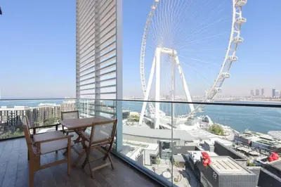 a table and chair on a balcony with a ferris wheel at Livbnb - Ain Dubai Panorama, 3BR with Maid's Room in Dubai