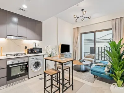 a kitchen and living room with a couch and a table at Cozy Stay 1BR in Azizi Pearl in Dubai