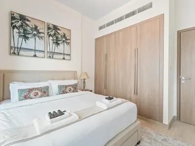 a bedroom with a large white bed with a wooden door at Cozy Stay 1BR in Azizi Pearl in Dubai