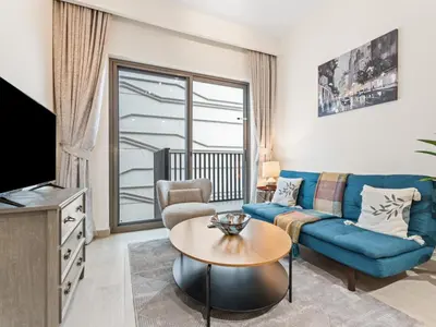 a living room with a blue couch and a table at Cozy Stay 1BR in Azizi Pearl in Dubai