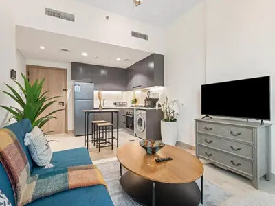 a living room with a blue couch and a table at Cozy Stay 1BR in Azizi Pearl in Dubai