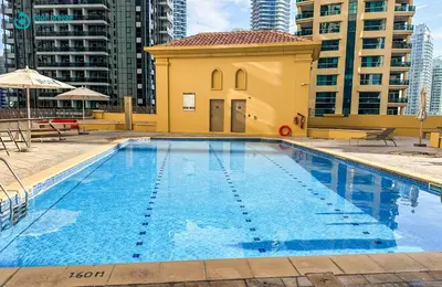 a large swimming pool with a small yellow building at Blue Breeze - Elegant 3BR Apt with Panoramic Marina Views in JBR in Dubai