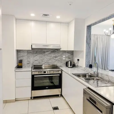 a white kitchen with a stove and a sink at Lamtara 3 MJL in Dubai