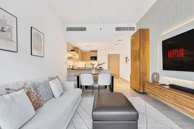 a living room with a couch and a kitchen at Stylish 1BR APT with Gym, Pool & Private Parking in Dubai
