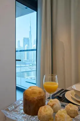 a table with a glass of orange juice and a cake at Full Burj Khalifa & Canal View I 7 Mins to Dubai Mall I Exclusive 2BHK For Up to 6 People in Dubai
