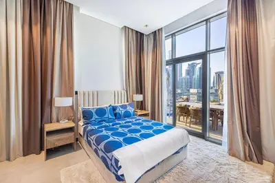 a bedroom with a blue bed and a large window at Waves - Stunning 1BR with Huge Terrace & Scenic Views in Dubai