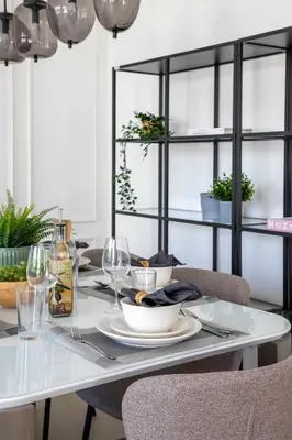 a dining room table with chairs and a white table with glasses at Frank Porter - Club Villas in Dubai